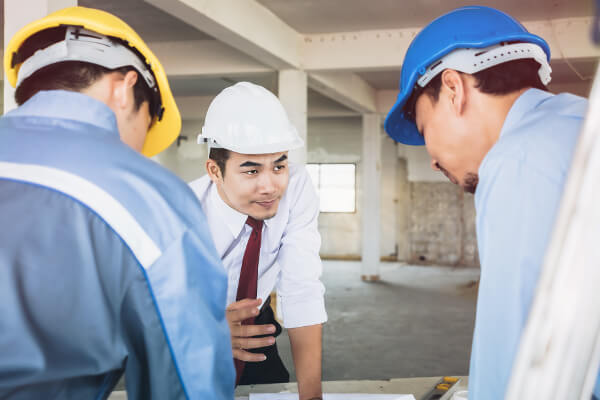 Architects on-site wearing hard hats, discussing plans for the building