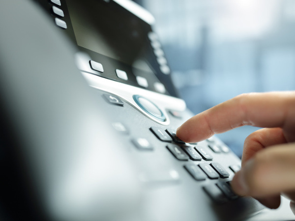 Close up of hand dialing a desktop telephone keypad