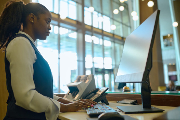 Side view of young woman in uniform looking at computer screen