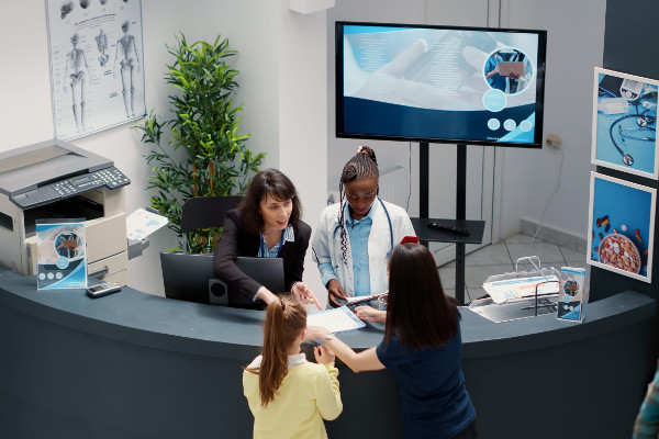 Secretary working at busy hospital reception desk