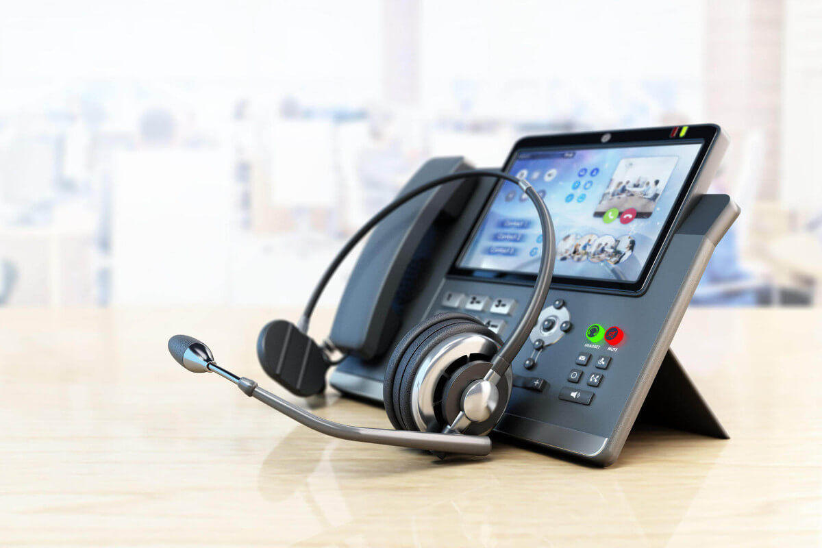 Modern VoIP phone and headset on a wooden office table