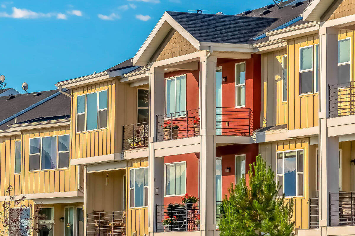 Townhomes in orange and yellow against blue sky on a sunny day