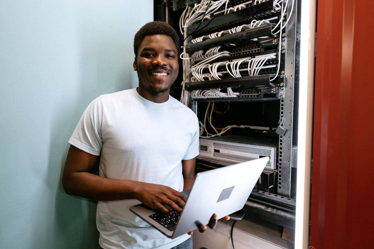 Smiling young professional managing servers with laptop