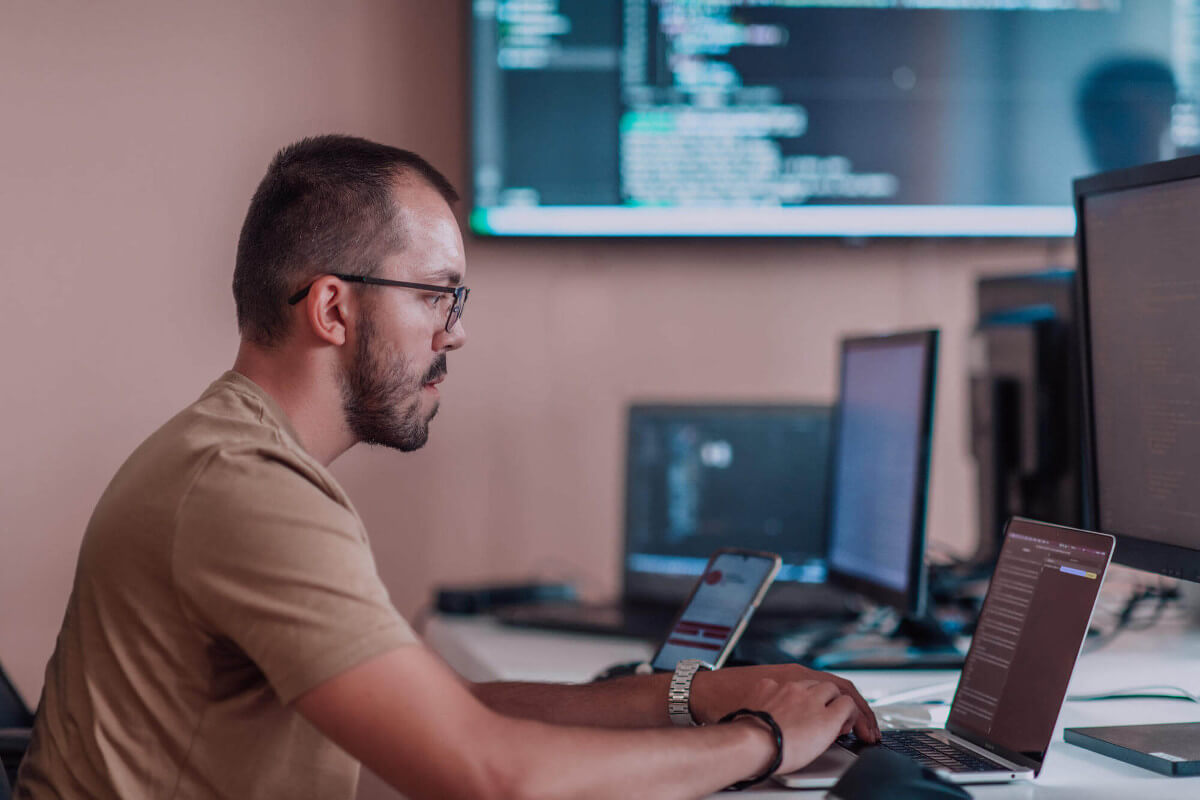 Side view of programmer sitting at desk working on a laptop 